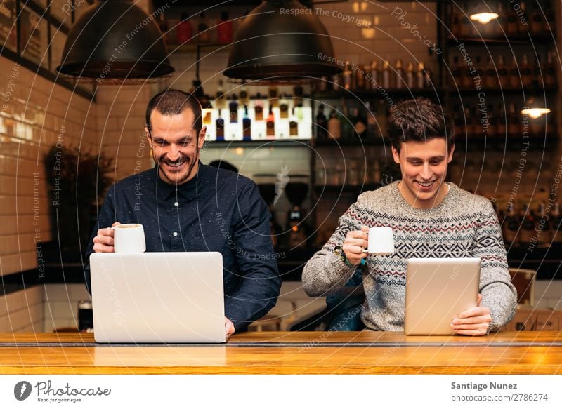 Freunde, die Handy und Laptop benutzen. Mann Kaffee Freundschaft Jugendliche Teamwork Menschengruppe Lifestyle PDA Mobile Mitteilung benutzend Text Computer