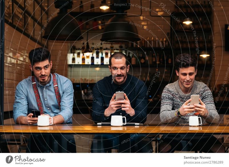 Freunde, die Handy und Laptop benutzen. Mann Kaffee Freundschaft Jugendliche Teamwork Menschengruppe Lifestyle PDA Mobile Mitteilung benutzend Text Computer