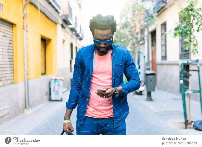 Afrikanischer junger Mann mit Handy auf der Straße. Lifestyle hören schwarz Amerikaner Stadt Porträt Telefon PDA Mobile Solarzelle Mitteilung Texten E-Mail