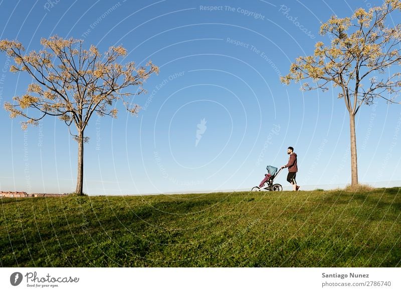 Vater und Sohn gehen durch den Park. Kinderwagen Joggen rennen laufen Buggy (Motorrad) Familie & Verwandtschaft Baby Jugendliche Tochter Außenaufnahme schön