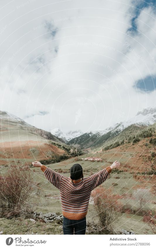 Junge Frau, die in einer wunderschönen Landschaft zwischen den Bergen steht. Berge u. Gebirge Pyrenäen Arme hoch Seite Dame Pullover Hut Hügel Schnee wunderbar