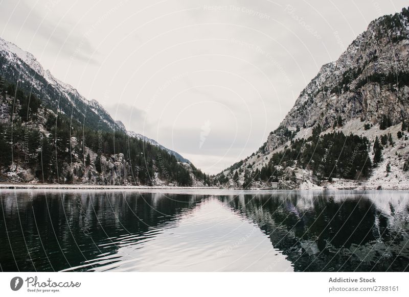 Wunderschöner See zwischen Hügeln im Schnee und bewölktem Himmel Pyrenäen Wolken wunderbar Wasser Oberfläche Berge u. Gebirge Höhe Baum erstaunlich Aussicht