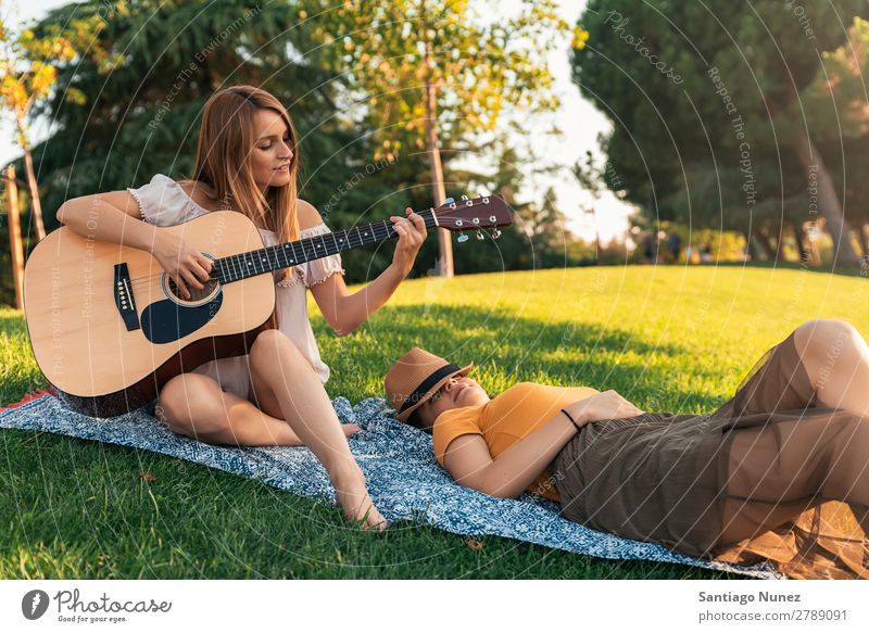 Schöne Frauen, die Spaß am Gitarrespielen im Park haben. Picknick Freundschaft Jugendliche Glück Gitarrenspieler Sommer Mensch Freude Spielen Musik Erwachsene