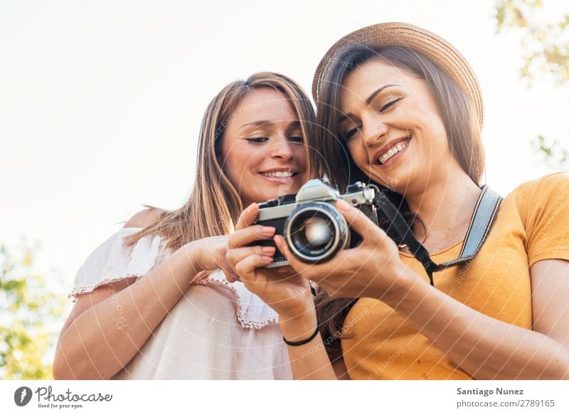 Fotografin, die ihrer Freundin ein Bild zeigt. Frau Picknick Freundschaft Jugendliche Park Glück Fotokamera Gitarre Gitarrenspieler Sitzung Fotografie zeigen