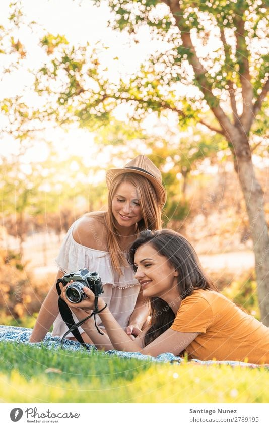 Fotografin, die ihrer Freundin ein Bild zeigt. Frau Picknick Freundschaft Jugendliche Park Glück Fotokamera Gitarre Gitarrenspieler Sitzung Fotografie zeigen