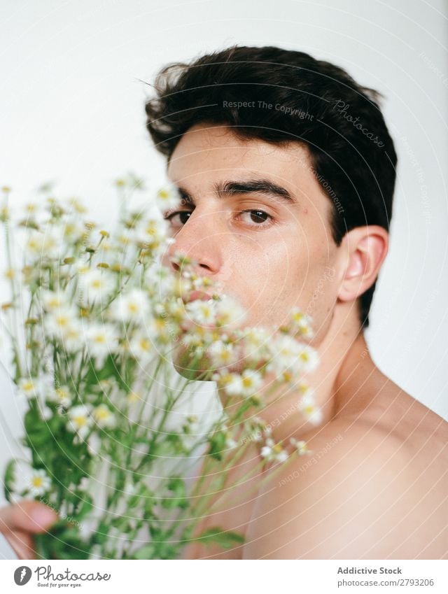 Junger Mann mit einem Blumenstrauß in den Händen. Mund Haufen Typ frisch Jugendliche brünett weiß ohne Hemd Überraschung Geschenk romantisch Gänseblümchen