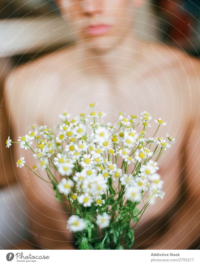 Junger Mann mit einem Blumenstrauß in den Händen. Mund Haufen Typ frisch Jugendliche brünett weiß ohne Hemd Überraschung Geschenk romantisch Gänseblümchen