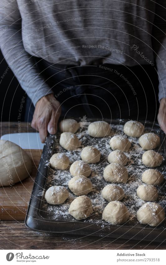 Person in der Nähe des Tabletts mit Teig und Mehl auf dem Tisch Kuchen Mensch Teigwaren Brotlaib Dunkelheit Lebensmittel Holz Backwaren Kulisse Mahlzeit