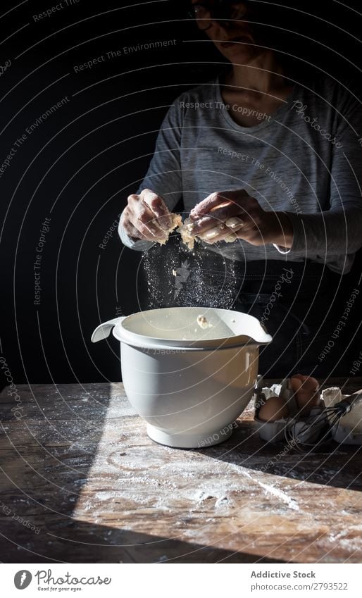 Person, die das Ei in der Schüssel auf dem Tisch knackt. Schalen & Schüsseln kochen & garen Mehl Rissbildung Holz Mahlzeit Handwerk brechen geschmackvoll Mensch