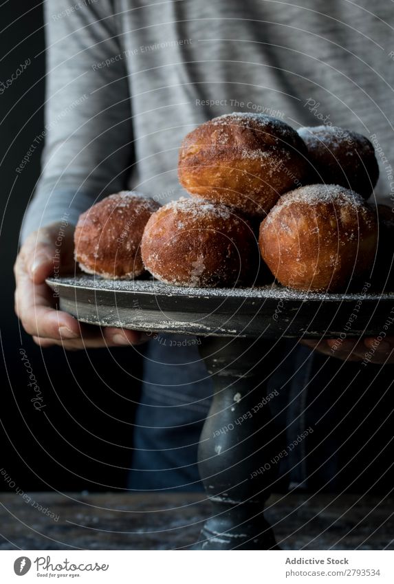 Person in der Nähe von gebackenen Kuchen auf dem Ständer auf dem Tisch Mensch Tablett Brotlaib Zucker gepulvert Dunkelheit Lebensmittel Holz Backwaren Kulisse