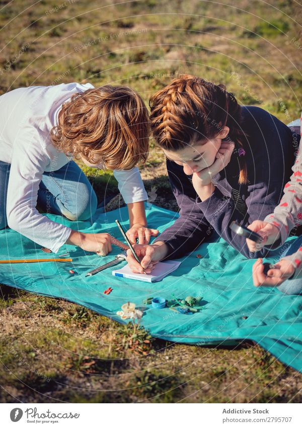 Frau macht Notizen und Kinder messen kleine Dinge auf der Bettdecke. Hinweis messend Bleistift Notizbuch Kunststoff Lineal Umwelt nehmen schreibend Messung Dame