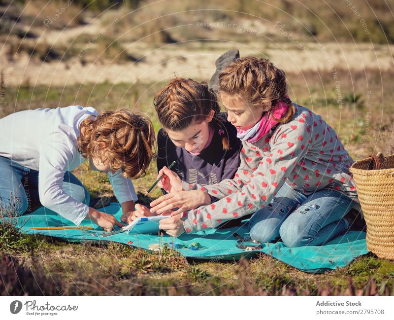 Frau macht Notizen und Kinder messen kleine Dinge auf der Bettdecke. Hinweis messend Bleistift Notizbuch Kunststoff Lineal Umwelt nehmen schreibend Messung Dame