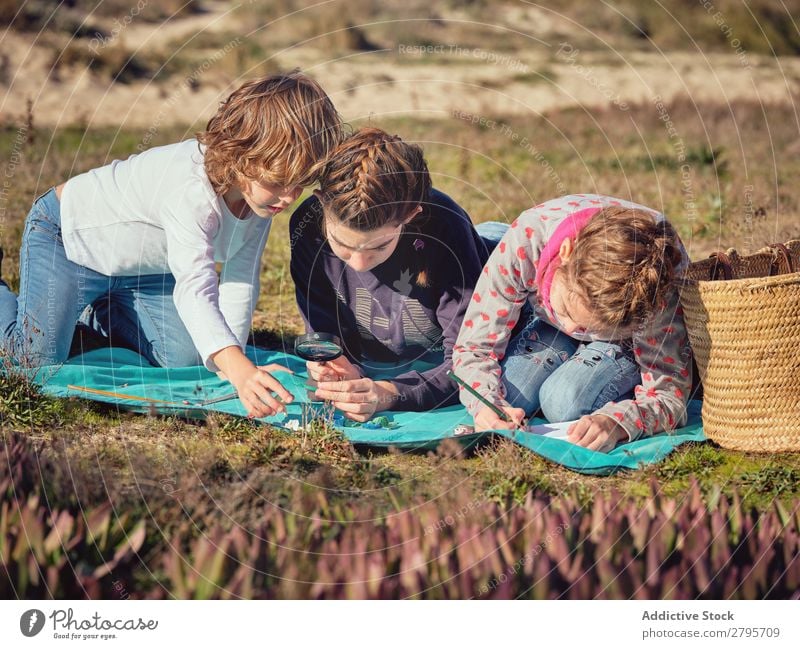 Frau macht Notizen und Kinder messen kleine Dinge auf der Bettdecke. Hinweis messend Bleistift Notizbuch Kunststoff Lineal Umwelt nehmen schreibend Messung Dame