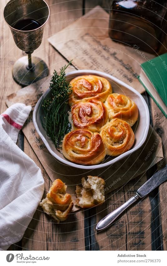 Wein in der Nähe von Gebäck und Kräutern Brötchen Küchenkräuter Tisch Kelch Teller Messer Lebensmittel Feinschmecker Snack rustikal Mahlzeit lecker