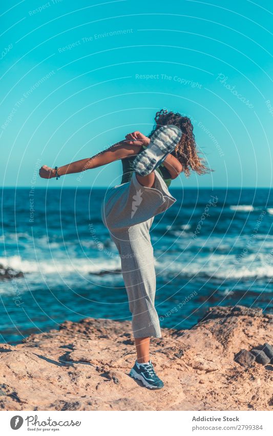 Anonyme Frau, die Luft an der Küste tritt. tretend Meer Himmel blau Schönes Wetter Lifestyle Freizeit & Hobby Wellen Stein Wasser Bewegung üben Gleichgewicht