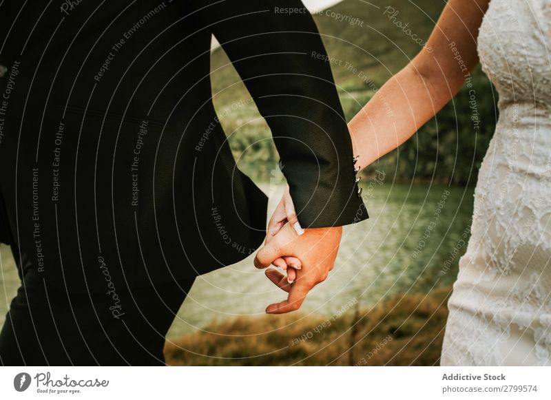 Bräutigam und Braut halten sich an der Küste die Hände. Paar Hochzeit Händchenhalten laufen Liebe Zusammensein striegeln romantisch Außenaufnahme Meer Kleid