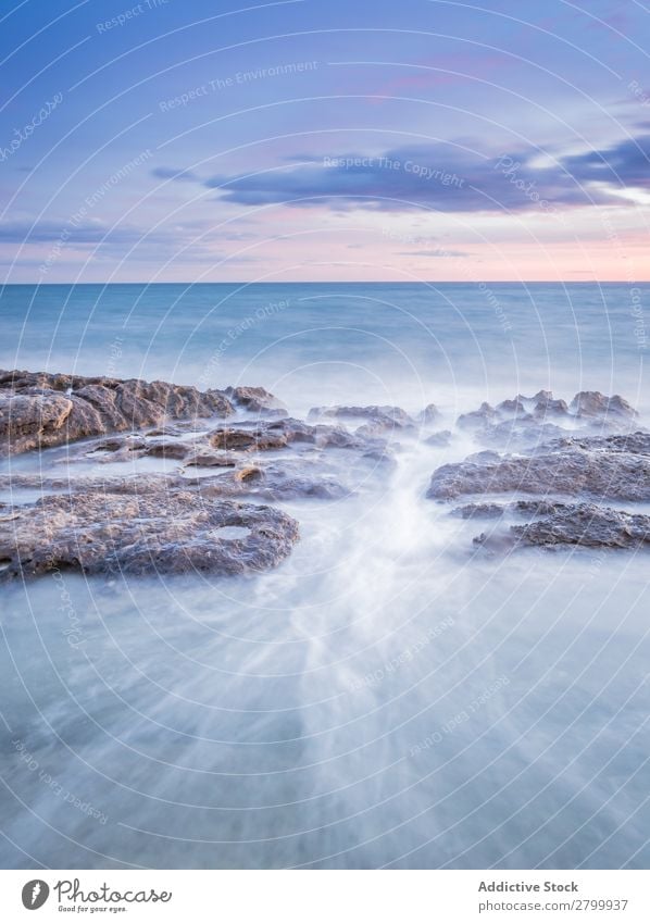 Das Meer wogt bei Sonnenuntergang in der Nähe von rauen Felsen. Wellen Abend Himmel Wolken Natur Meereslandschaft Wasser Stein rollierend platschen Landschaft