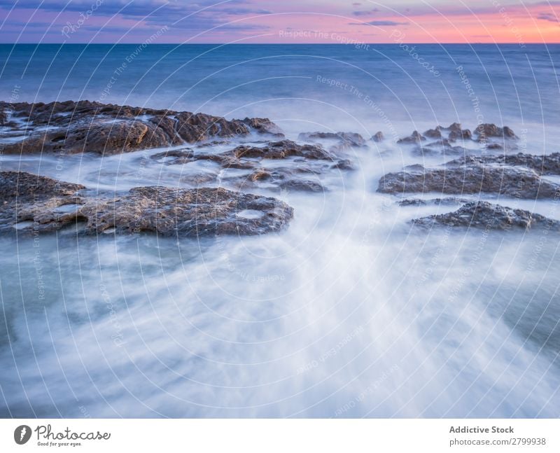 Das Meer wogt bei Sonnenuntergang in der Nähe von rauen Felsen. Wellen Abend Himmel Wolken Natur Meereslandschaft Wasser Stein rollierend platschen Landschaft