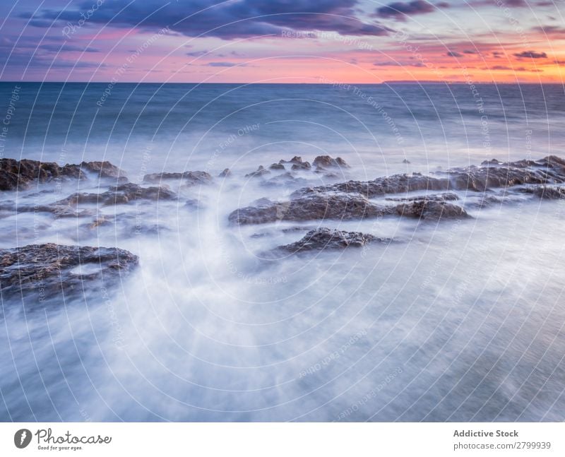 Das Meer wogt bei Sonnenuntergang in der Nähe von rauen Felsen. Wellen Abend Himmel Wolken Natur Meereslandschaft Wasser Stein rollierend platschen Landschaft