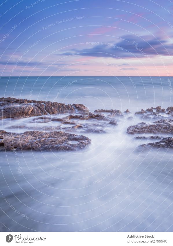 Das Meer wogt bei Sonnenuntergang in der Nähe von rauen Felsen. Wellen Abend Himmel Wolken Natur Meereslandschaft Wasser Stein rollierend platschen Landschaft