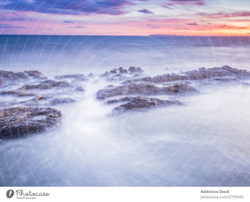 Das Meer wogt bei Sonnenuntergang in der Nähe von rauen Felsen. Wellen Abend Himmel Wolken Natur Meereslandschaft Wasser Stein rollierend platschen Landschaft