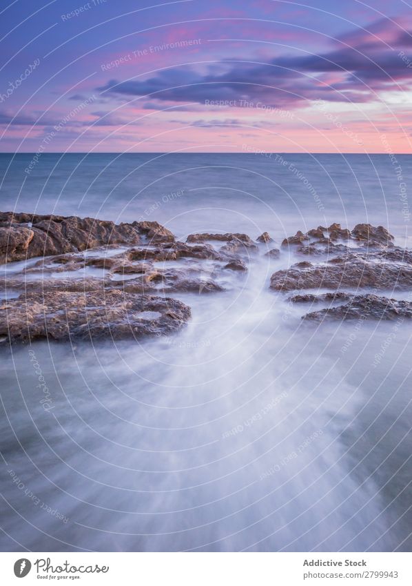 Das Meer wogt bei Sonnenuntergang in der Nähe von rauen Felsen. Wellen Abend Himmel Wolken Natur Meereslandschaft Wasser Stein rollierend platschen Landschaft