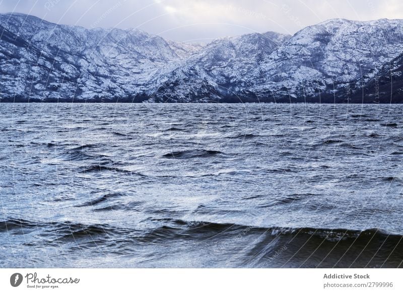 Ufer mit Bergen am Wasser Küste Schnee Berge u. Gebirge Felsen Klippe Stein Himmel Wolken Oberfläche winkend erstaunlich weiß natürlich Aussicht Hügel Landen