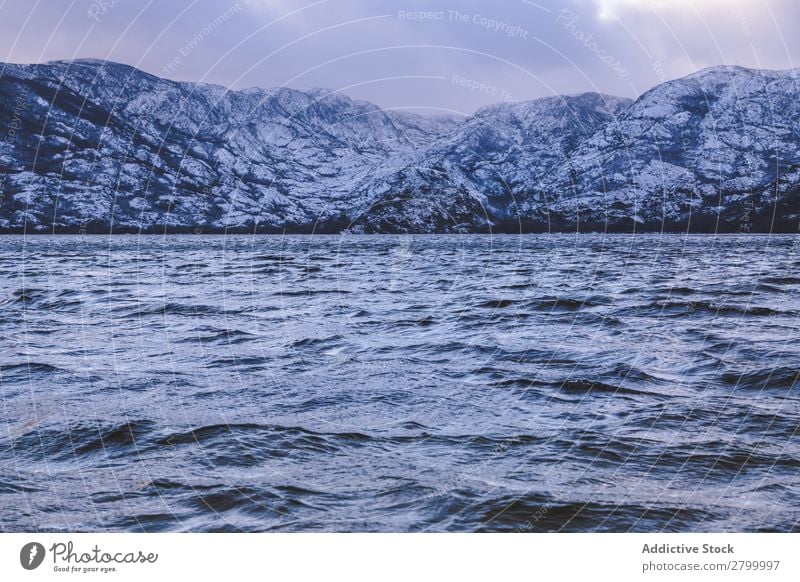 Ufer mit Bergen am Wasser Küste Schnee Berge u. Gebirge Felsen Klippe Stein Himmel Wolken Oberfläche winkend erstaunlich weiß natürlich Aussicht Hügel Landen