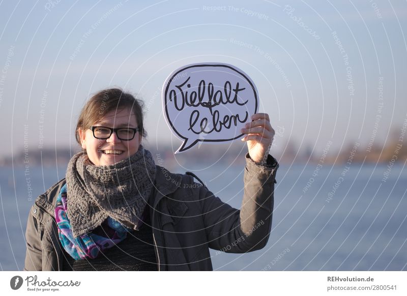 Frau hält Sprechblase Vielfalt leben Herbst Jacke Text Worte haben Macht Lächeln Brille See Natur halten festhalten feminin Erwachsene Schilder & Markierungen