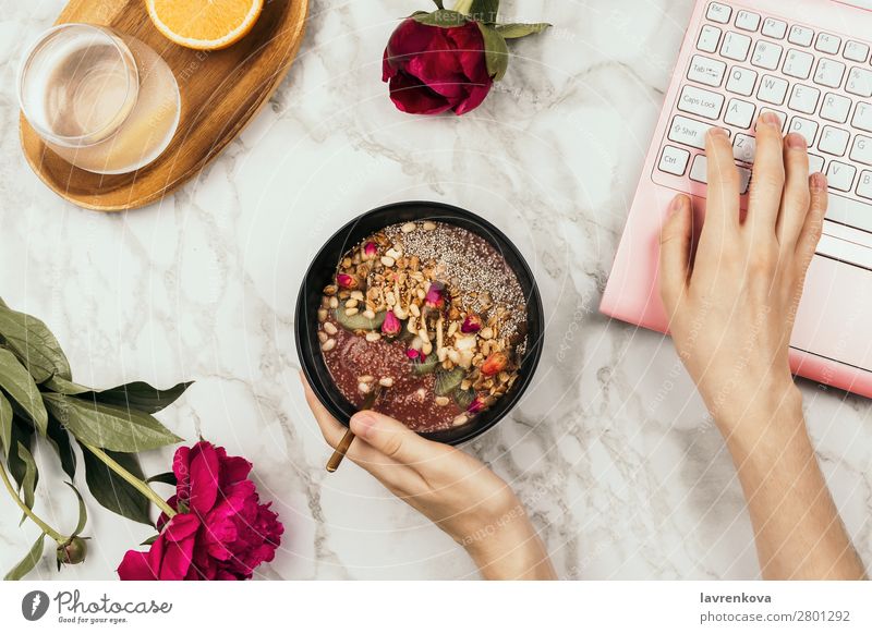 Flachlegen der Frauenhände mit Smoothie-Schale und Laptop Notebook Orange Wasser Frucht Milchshake Chiapudding Diät Entzug Schalen & Schüsseln Junge Frau Snack