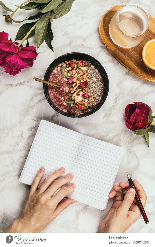 Hände halten Smoothie-Schale mit Notizbuch, Pfingstrosen und Wasser. organisch Zutaten Schreibstift Aussicht Top Marmor Snack Belag Müsli legen flach Blume