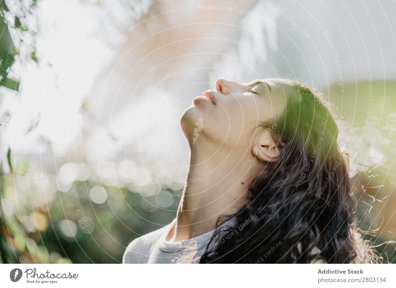 Fröhliche Frau lächelnd im Garten Hinterhof Lächeln Sträucher Jugendliche Sonnenstrahlen Tag gestikulieren Sommer Stil lässig trendy Park harmonisch Idylle