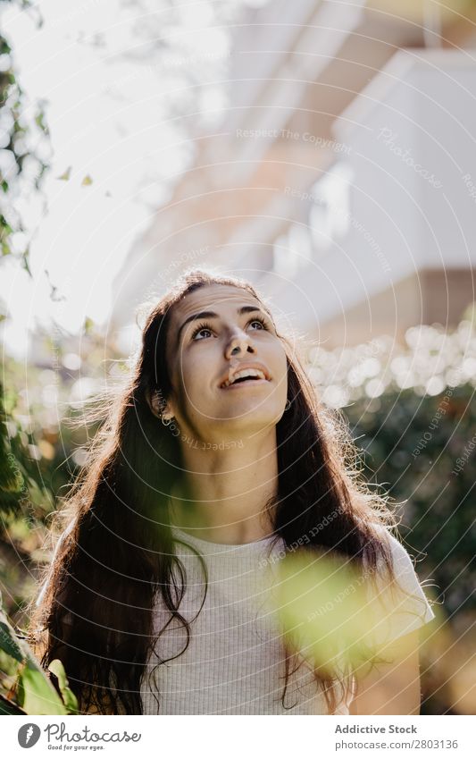 Fröhliche Frau im Garten Hinterhof brünett Lächeln Sträucher Jugendliche Sonnenstrahlen Tag gestikulieren Sommer Stil lässig trendy Park harmonisch Idylle Glück