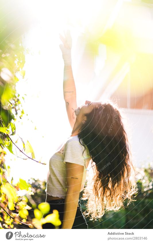 Fröhliche Frau im Garten Hinterhof brünett Lächeln Sträucher Jugendliche Sonnenstrahlen Tag gestikulieren Sommer Stil lässig trendy Park harmonisch Idylle Glück