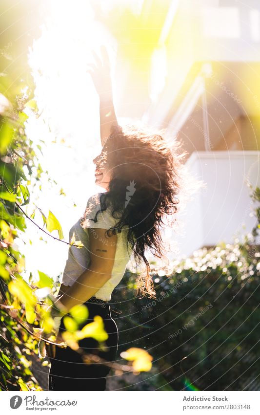 Fröhliche Frau im Garten Hinterhof brünett Lächeln Sträucher Jugendliche Sonnenstrahlen Tag gestikulieren Sommer Stil lässig trendy Park harmonisch Idylle Glück