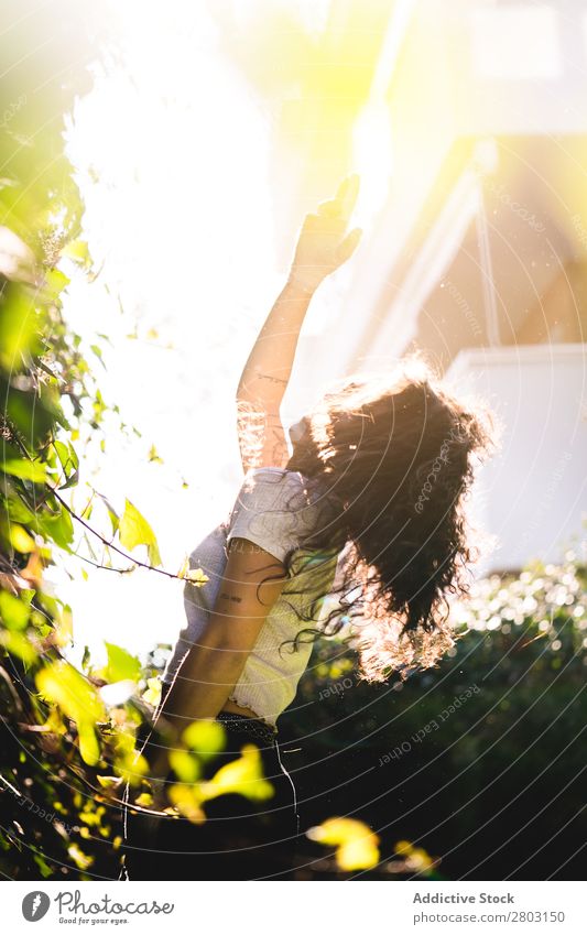 Fröhliche Frau im Garten Hinterhof brünett Lächeln Sträucher Jugendliche Sonnenstrahlen Tag gestikulieren Sommer Stil lässig trendy Park harmonisch Idylle Glück