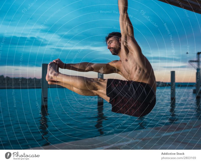 Athletischer Mann balanciert auf Gymnastikringen Sportler Gleichgewicht gymnastisch Stauanlage Ring ohne Hemd Wasser Großstadt Abend sportlich Jugendliche