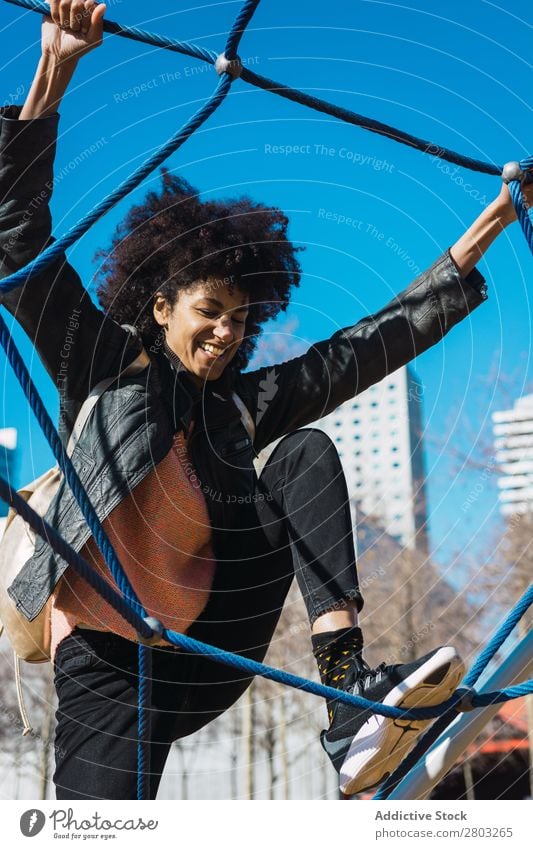 Frau mit Afrohaar klettert bei Kinderattraktionen. Aktion Afrikanisch Afro-Look schwarz heiter Kindheit Klettern niedlich Gerät Familie & Verwandtschaft Freude