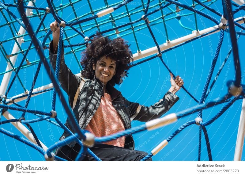 Frau mit Afrohaar klettert bei Kinderattraktionen. Aktion Afrikanisch Afro-Look schwarz heiter Kindheit Klettern niedlich Gerät Familie & Verwandtschaft Freude