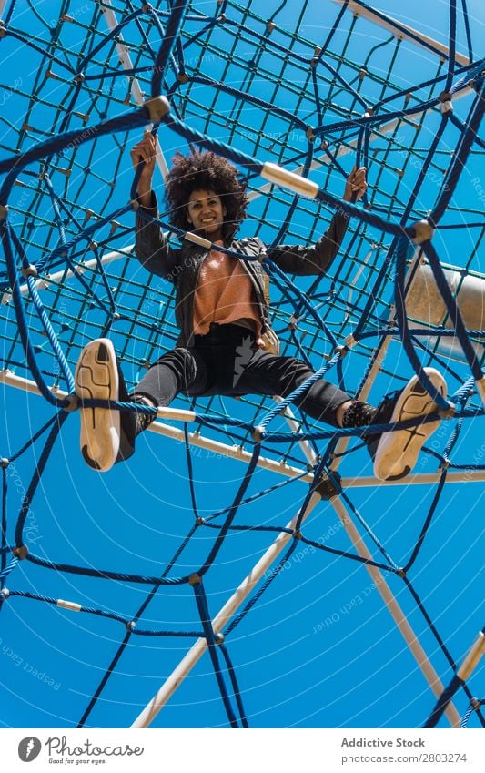 Frau mit Afrohaar klettert bei Kinderattraktionen. Aktion Afrikanisch Afro-Look schwarz heiter Kindheit Klettern niedlich Gerät Familie & Verwandtschaft Freude