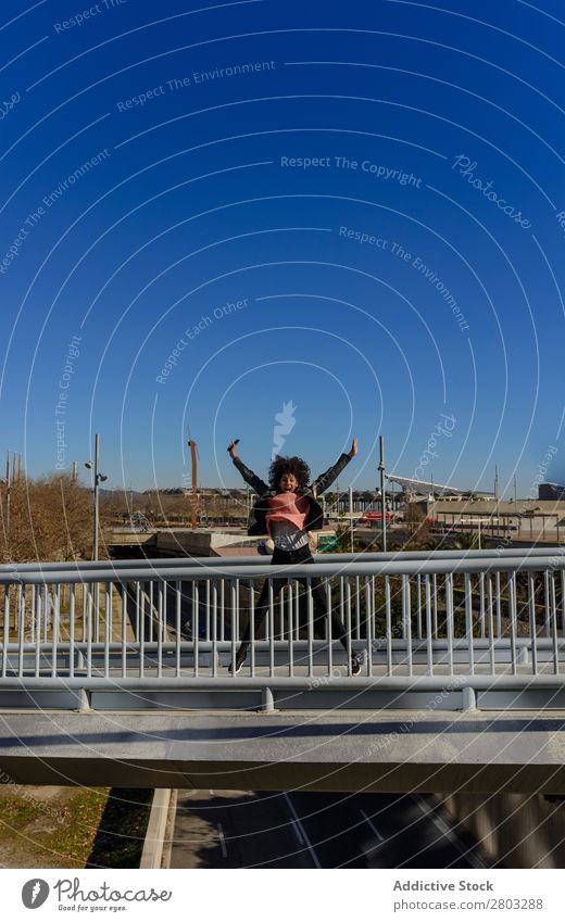 Frau mit Afro-Haaren, die vor Freude auf der Straße springt. Afrikanisch Afro-Look Amerikaner Hintergrundbild schön schwarz lässig heiter Farbe Energie Genuss