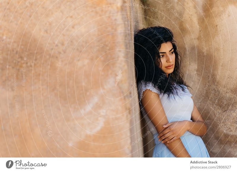 Schöne ethnische Frau in der Nähe einer schäbigen Mauer. Marokkaner Wand urwüchsig elegant anlehnen Außenseite Gebäude Jugendliche Model dünn dreckig genießen