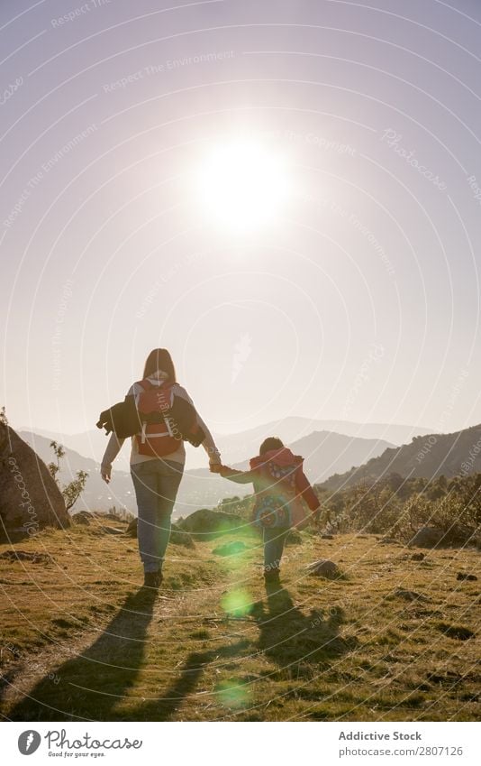 Mama hält die Hand der Tochter und wandert bei Sonnenuntergang durch die Natur. Mutter Mädchen Kind Familie & Verwandtschaft Zusammensein laufen Liebe Freude