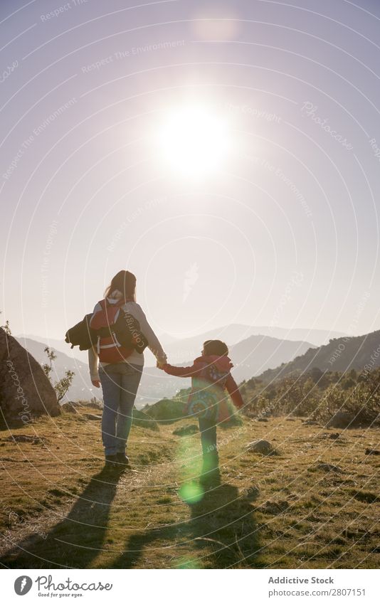 Mama hält die Hand der Tochter und wandert bei Sonnenuntergang durch die Natur. Mutter Mädchen Kind Familie & Verwandtschaft Zusammensein laufen Liebe Freude