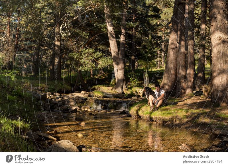 Junger Mann ruht sich nach dem Abenteuer mit seinem Hund am Wasserfall aus. Natur Sommer Ferien & Urlaub & Reisen genießend Gesundheit Körper Entwurf grün