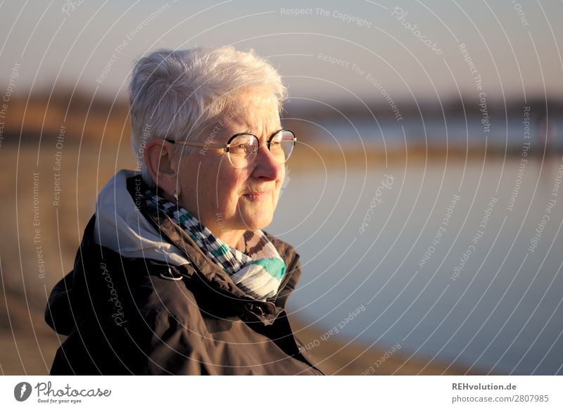 Seniorin im Abendlicht blickt in die Ferne See Wasser weite nachdenklich Brille Jacke Zukunft sorgen Natur Umwelt kritisch Mensch ruhig stille Himmel