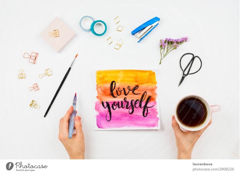 Handschriftliches Schild Love Yourself, Aquarell und Briefpapier Junge Frau schreibend Text Idee körperpositiv Motivation mehrfarbig Buchstaben Beschriftung