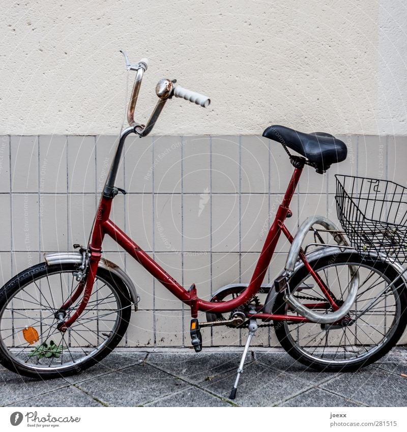 City-Flitzer Mauer Wand Fahrrad alt hässlich retro verrückt rot schwarz weiß Vergangenheit Klapprad Kettenschloss Einkaufskorb Schloss Farbfoto Gedeckte Farben