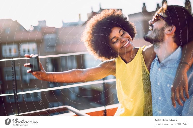 Junges multikulturelles Paar, das Selfie nimmt und verliebt auf dem Dach lacht. anhänglich Afrikanisch schön Freund Kaukasier Solarzelle Datierung