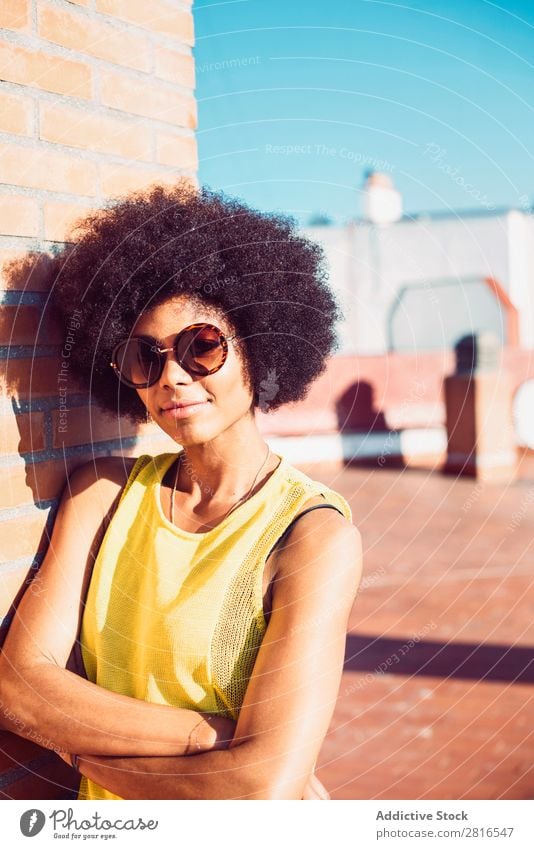 Junge schöne afroamerikanische Frau, die posiert und lächelt, während sie an der Ziegelwand steht. Afrikanisch Amerikaner charmant Backstein Model Hand